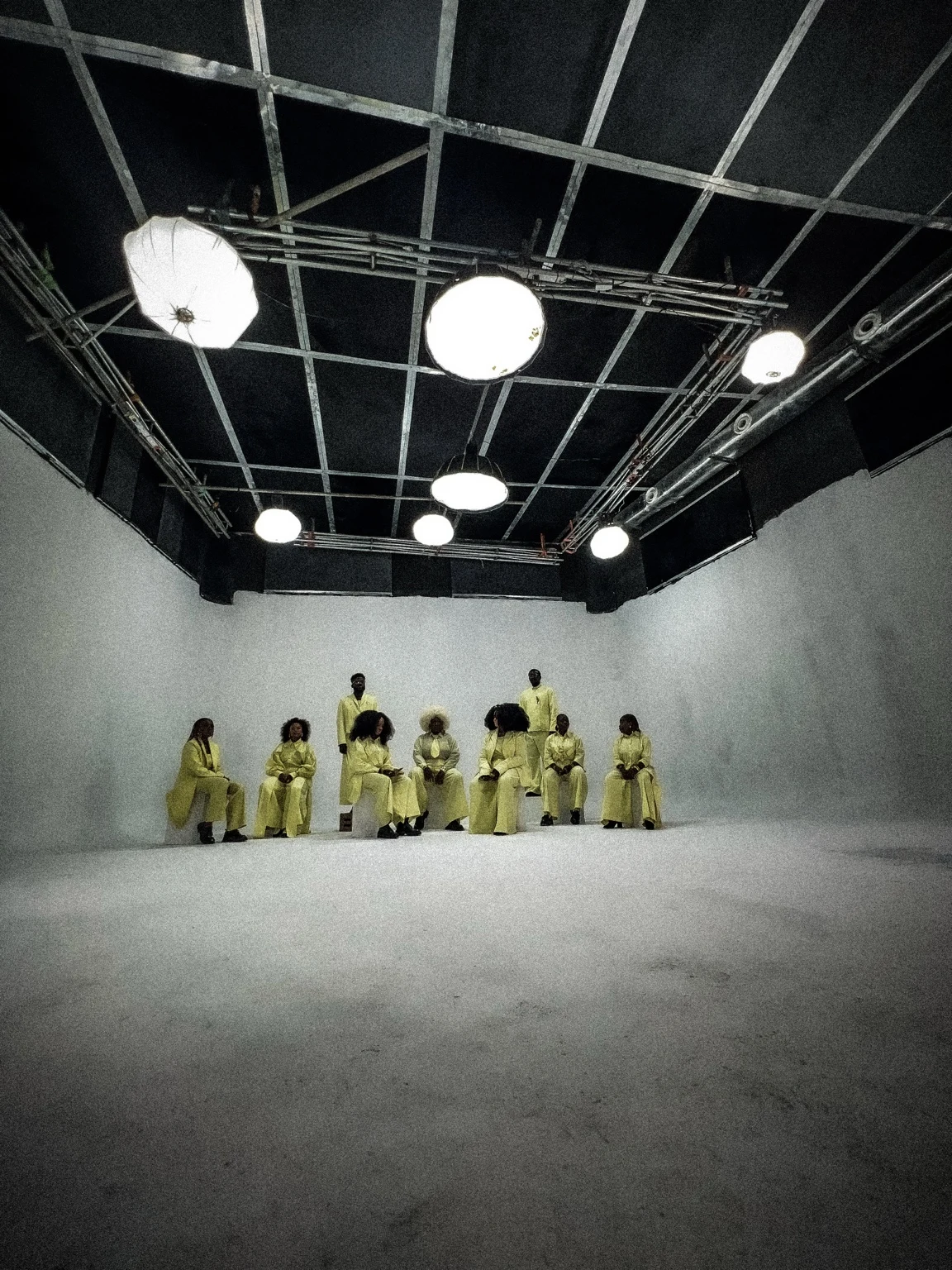 Performers in yellow beneath studio lights